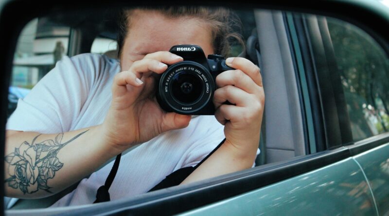 automobile, camera, girl, woman, lens, photographer, photography, driving a car, equipment, aperture, canon, tattoo, white, turquoise, black, gray, skin color, the frontal perspective